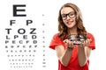 Teenage girl holding glasses over eye test chart Royalty Free Stock Photo
