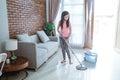 Teenage girl holding a mop stick doing household chores is mopping the living room Royalty Free Stock Photo