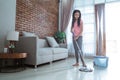 Teenage girl holding a mop stick doing household chores is mopping the living room Royalty Free Stock Photo