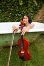 Teenage girl holding violin and fiddlestick outdoor in bathtub Royalty Free Stock Photo