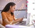 Teenage Girl At Home In Bedroom Looking At Mobile Phone And Studying Using Laptop Computer Royalty Free Stock Photo