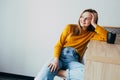 Teenage girl in home interior looks left side, lean on wooden table with black cup of coffee and sitting on white modern chair. Be Royalty Free Stock Photo