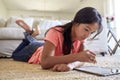 Teenage girl at home lying on the floor in the living room using tablet computer and stylus, low angle, close up Royalty Free Stock Photo