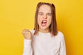 Teenage girl in jumper with ponytails clenches fist and teeth expresses negative emotions being fed up of something has irritated Royalty Free Stock Photo