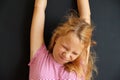 Teenage girl just woke up and stretching, portrait on black background