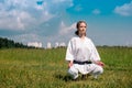 Teenage girl karateka before starting training outdoor enters the mokuso meditative state in the seiza pose