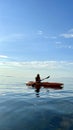 teenage girl is kayaking Pelican at sunset in Pacific Ocean only silhouette of Kayak Paddles is visible she swims sunny