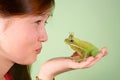 Teenage girl kissing Tree frog Litoria infrafrenata with a crown on his head Royalty Free Stock Photo
