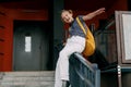 A teenage girl laughs and slides down the railing on her way to school. A cheerful girl hurries to school