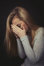 Teenage girl with long blond hair crying with her hands up to her face. Royalty Free Stock Photo