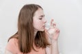 A teenage girl with long blond hair drinks water from a glass glass Royalty Free Stock Photo