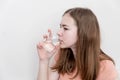 A teenage girl with long blond hair drinks water from a glass glass Royalty Free Stock Photo