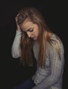 Teenage girl with long blond hair sitting looking sad. Royalty Free Stock Photo