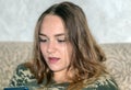 Teenage girl with long hair, sitting indoors and looking at the phone