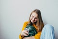 Teenage girl looking on cellphone and smiles chatting with friends. Beautiful girl in yellow sweater and blue jeans holding mobile Royalty Free Stock Photo