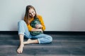 Teenage girl looking on cellphone and smiles chatting with friends. Beautiful girl in yellow sweater and blue jeans holding mobile Royalty Free Stock Photo