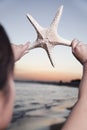 Teenage girl looking and holding up starfish Royalty Free Stock Photo