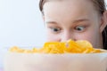 A teenage girl looks with wild, wide-open eyes at a bowl full of chips, face close-up