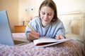 Teenage Girl Lying On Bed In Bedroom With Laptop Studying And Home Schooling Royalty Free Stock Photo