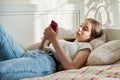 Teenage girl lying in bed using smartphone for leisure communication Royalty Free Stock Photo