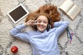 Teenage girl lying on floor carpet, listening to music Royalty Free Stock Photo