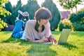 Teenage girl lying on the grass using a laptop Royalty Free Stock Photo