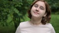 A teenage girl makes funny faces at the camera in the park. Foolishness and fun. Frames in 4K format