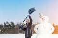 teenage girl is making a snowman and holding a shovel. The concept of active winter recreation. Family vacation. Royalty Free Stock Photo