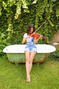 Teenage girl making terrible sounds on violin outdoor Royalty Free Stock Photo