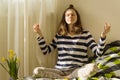 Teenage girl meditating and smiling while sitting in yoga pose on the bed Royalty Free Stock Photo