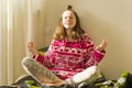 Teenage girl meditating and smiling while sitting in yoga pose on the bed Royalty Free Stock Photo