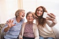 A teenage girl, mother and grandmother with smartphone at home. Royalty Free Stock Photo