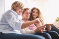 A teenage girl, mother and grandmother with tablet at home. Royalty Free Stock Photo