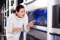 Teenage girl near big aquarium is pointing to interesting model of aquariums Royalty Free Stock Photo