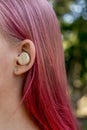 Teenage girl with ombre colored pink hair with wireless earbuds earphones in her ear. Music phone calls podcast audiobooks