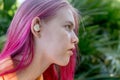 Teenage girl with ombre colored pink hair with wireless earbuds earphones. Music phone calls podcast audiobooks listening