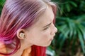 Teenage girl with ombre colored pink hair with wireless earbuds earphones. Music phone calls podcast audiobooks listening