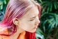 Teenage girl with ombre colored pink hair with wireless earbuds earphones. Music phone calls podcast audiobooks listening