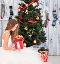 Teenage girl opening Christmas present near New Year tree Royalty Free Stock Photo