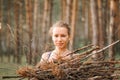 Teenage girl with pimple skin collect branches firewood for a campfire while traveling through a summer forest in nature. young ha Royalty Free Stock Photo