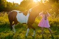 Teenage girl in pink dress walking with a horse at sunset Royalty Free Stock Photo