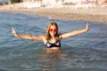 Teenage girl in pink sunglasses having fun on the beach in the sea, playing with splashes. Fun on summer hloiday concept Royalty Free Stock Photo