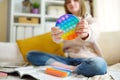 Teenage girl playing with rainbow pop-it fidget toy while studying at home. Teen kid with trendy stress and anxiety relief