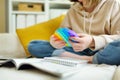 Teenage girl playing with rainbow pop-it fidget toy while studying at home. Teen kid with trendy stress and anxiety relief