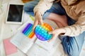 Teenage girl playing with rainbow pop-it fidget toy while studying at home. Teen kid with trendy stress and anxiety relief Royalty Free Stock Photo