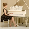 A teenage girl is playing on a white grand piano. Royalty Free Stock Photo