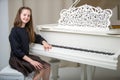A teenage girl is playing on a white grand piano. Royalty Free Stock Photo