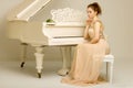 A teenage girl is playing on a white grand piano. Royalty Free Stock Photo