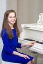 A teenage girl is playing on a white grand piano. Royalty Free Stock Photo