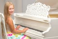 A teenage girl is playing on a white grand piano. Royalty Free Stock Photo